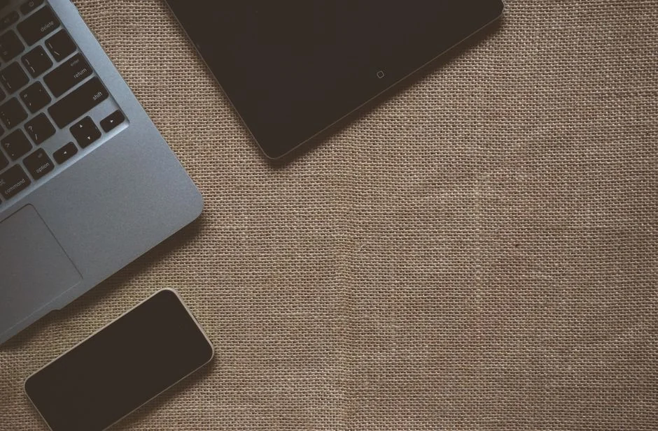 Close-up of a laptop and tablet on a wooden desk, showcasing modern technology.